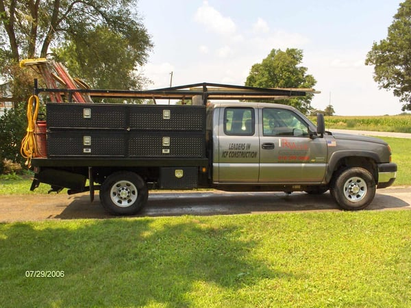 Gray R Value Homes construction truck with storage compartments, labeled -Leaders in ICF Construction,- parked on a driveway in West Michigan