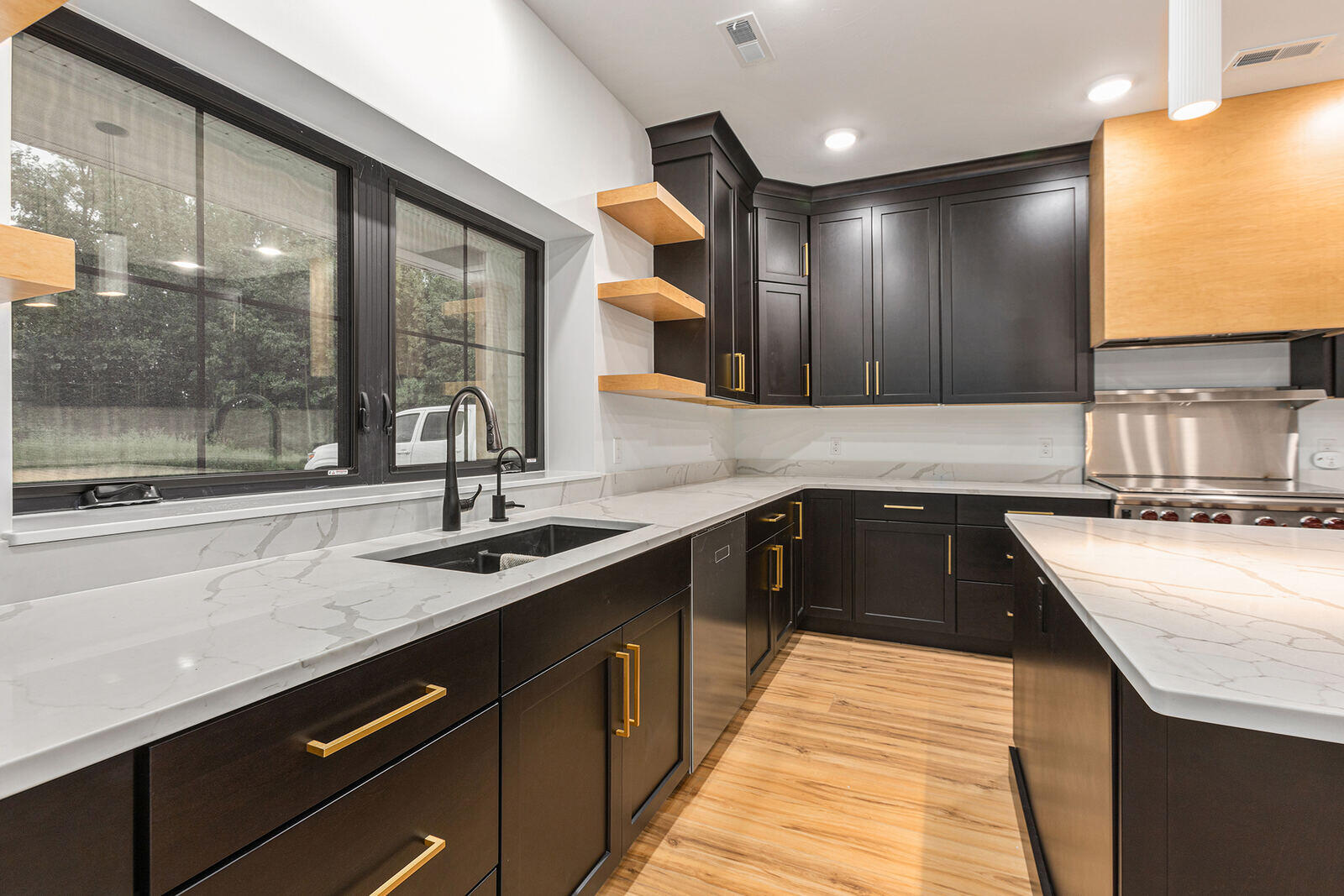 Elegant kitchen sink area with black cabinets and gold handles in a West Michigan custom home