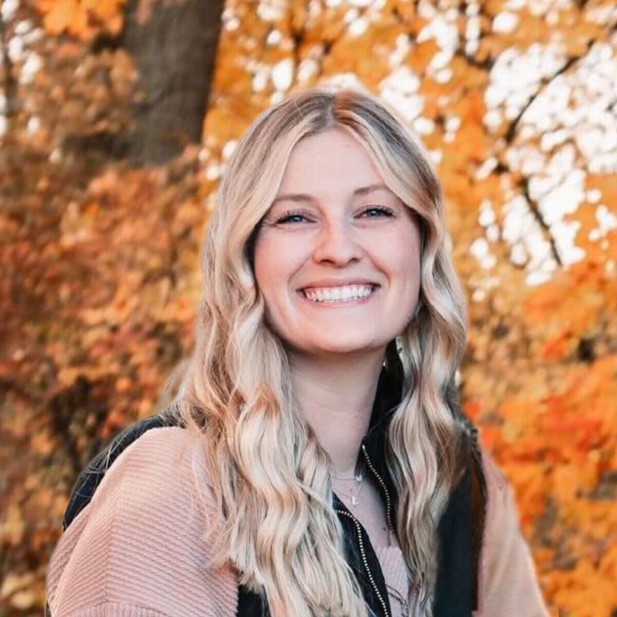 Outdoor portrait of Megan with a fall foliage background, a team member at R Value Homes in West Michigan