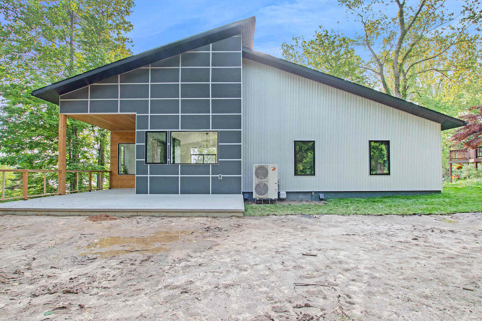 Side view of a modern custom home with a spacious porch by R Value Homes, West Michigan