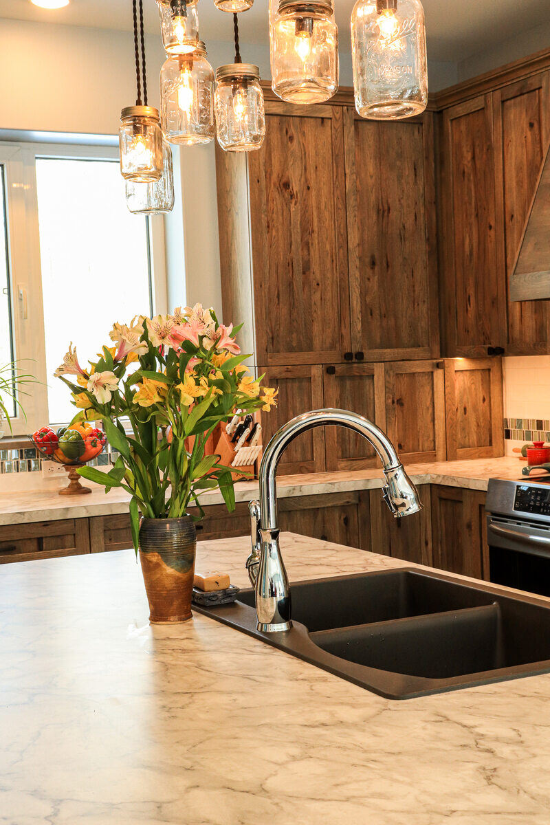 Modern kitchen island with marble countertops and mason jar pendant lights by R-Value Homes, West Michigan