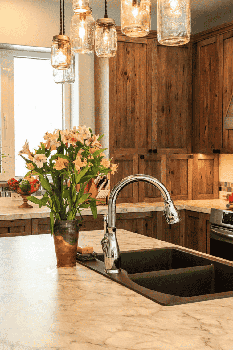 Modern kitchen island with marble countertops and mason jar pendant lights by R-Value Homes, West Michigan